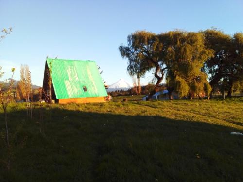 eine alte Scheune mit einem grünen Dach auf einem Feld in der Unterkunft Linda cabaña en Puyehue con vista al volcán in Ñilque