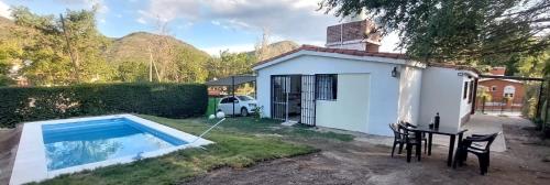 a small white house with a table and a small pool at Don Edelmi in Villa Carlos Paz