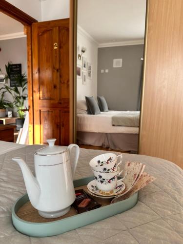a tray with a tea pot and cups on a bed at Malahide Guest Rooms in Malahide