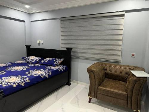 ein Schlafzimmer mit einem Bett und einem Stuhl in der Unterkunft Wells Homes in Kwedonu