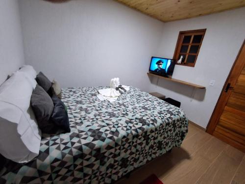 1 dormitorio con 1 cama y mesa con TV en Pousada Lofts e Suítes Campos en Campos do Jordão