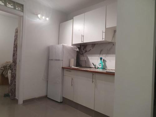 uma cozinha com armários brancos e um frigorífico branco em Casa Vive em Puerto de la Cruz