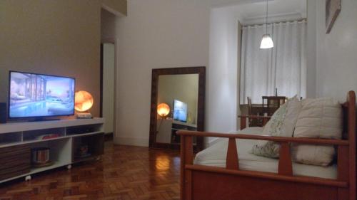 uma sala de estar com uma cama e uma televisão de ecrã plano em Solar Del Passo no Rio de Janeiro