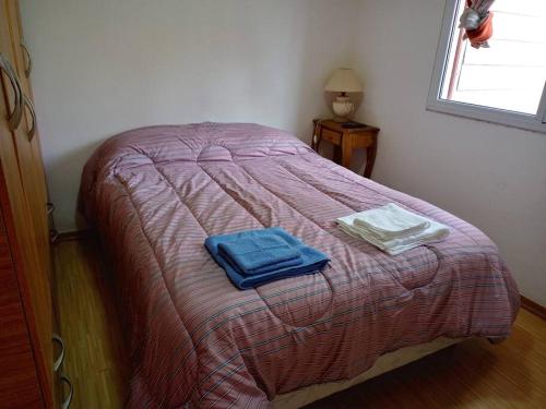 a bed with two towels sitting on top of it at Casa Grilli cerca de la terminal in Río Gallegos