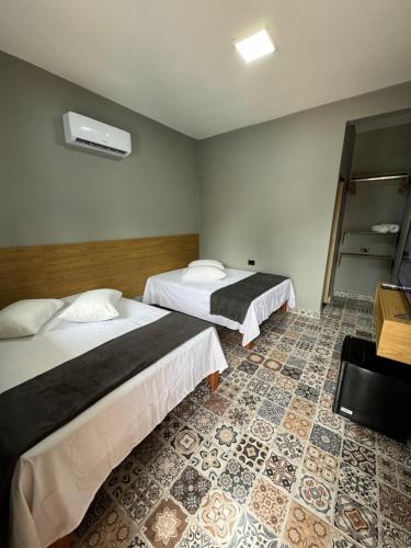Habitación de hotel con 2 camas y suelo de baldosa. en Santa Clara Pousada en Guarujá
