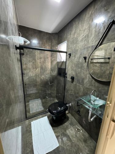 a bathroom with a black toilet and a shower at Santa Clara Pousada in Guarujá