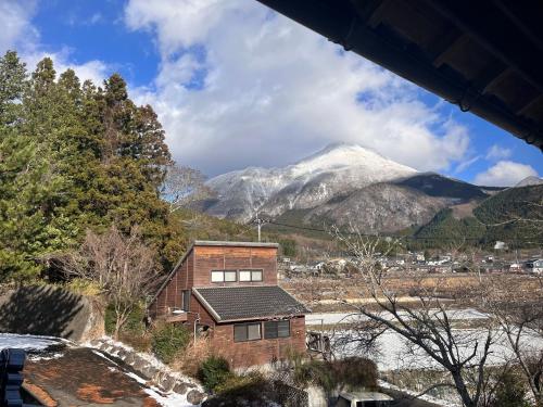 a house in front of a snow covered mountain at 湯布院我楽珍民泊Yufuin Garakuchin in Yufuin