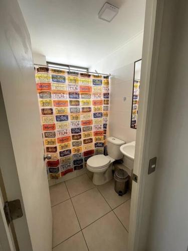 a bathroom with a toilet and a wall of signs at Arriendo departamento Amunategui in Iquique