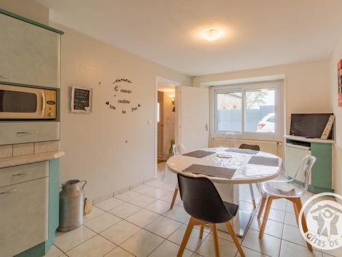 une cuisine avec une table et des chaises et un micro-ondes dans l'établissement Gîte familial avec belle cour, 3 chambres, proche vignobles et activités, au calme en campagne angevine - FR-1-622-11, à Saint-Georges-du-Puy-de-la-Garde