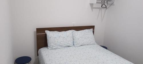 um quarto com uma cama com lençóis brancos e almofadas em Quarto Hokkaido na Sakura House em Indaiatuba