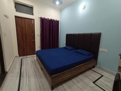 a bedroom with a bed with blue sheets and a door at Deepak Homestay in Rishīkesh