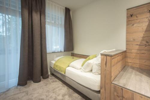 1 dormitorio con 1 cama y una ventana con cortinas en Hotel dasZimmermann en Todtmoos