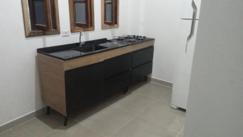 a kitchen with a sink and a refrigerator at Cantinho do Sossego - kitnets in Cananéia