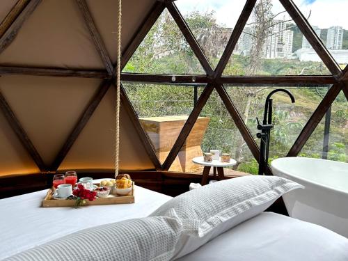 a room with a bed with a tray of food and a tub at Domo Vila da Serra in Nova Lima