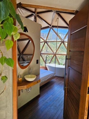 a bathroom with a tub and a sink and a mirror at Domo Vila da Serra in Nova Lima