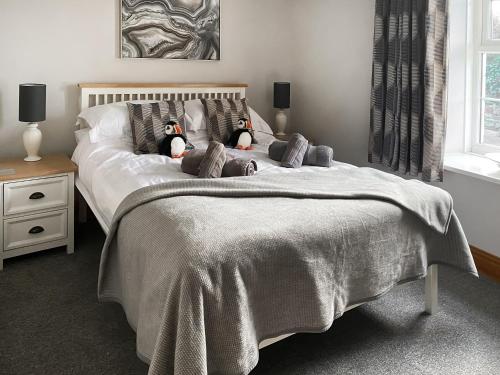 un dormitorio con dos pingüinos de peluche en una cama en West View Cottage, en Seahouses