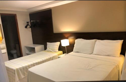 a hotel room with two beds with white sheets at Pacific Flat & Confort à Beira Mar in João Pessoa