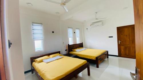 2 Betten in einem kleinen Zimmer mit gelber Bettwäsche in der Unterkunft villa24.trinco in Trincomalee