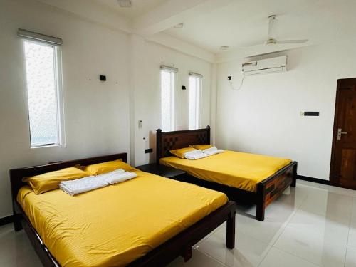 two beds in a room with yellow sheets at villa24.trinco in Trincomalee