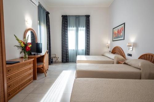 Habitación de hotel con 3 camas y escritorio. en Hotel Corallo en Taormina