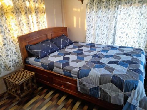 a bedroom with a bed with a checkered comforter at Bethel homestay Delo in Kalimpong