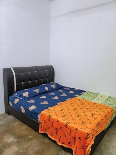 uma cama com um edredão laranja e azul em Bukit Bayan TOWNHOUSE em Sungai Petani