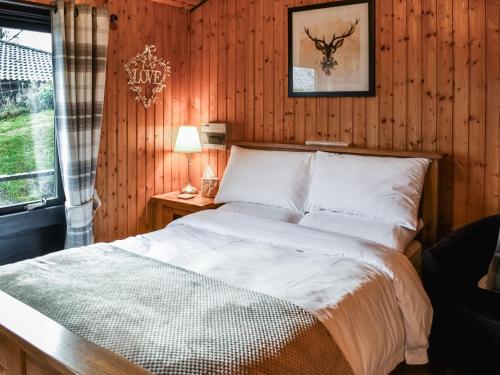 a bedroom with a bed with a wooden wall at Glendowlin Lodge Retreat in Tirril