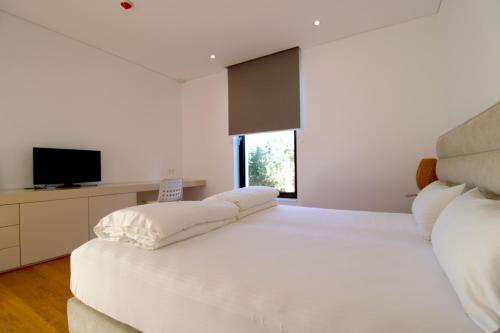 a white bedroom with a large white bed with pillows at Deluxe Villa Jante Infinity Pool in Durrës