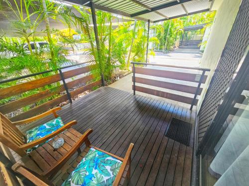 a wooden deck with a bench and palm trees at Emerald Motel Apartments in Emerald