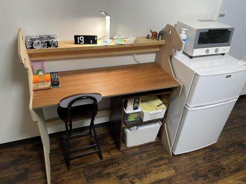 a desk with a computer and a chair next to a refrigerator at 11月フルリフォーム 12月オープン恐竜一色ゲストハウスDinosaur Guesthouse in Katsuyama