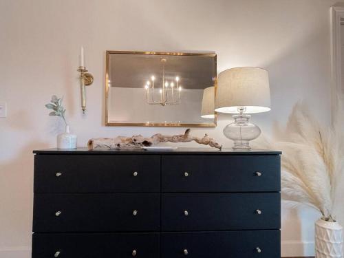 eine schwarze Kommode mit einer Lampe und einem Spiegel in der Unterkunft Bayside Bungalow in Norfolk