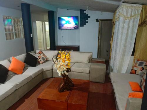 una sala de estar con sofá y un jarrón de flores en Acogedor apartamento en Píllaro, en Píllaro