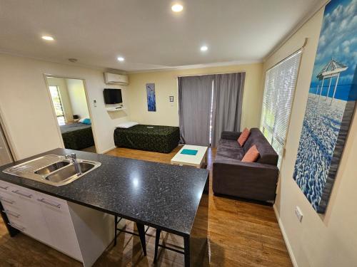 cocina y sala de estar con fregadero y sofá en Emerald Motel Apartments, en Emerald