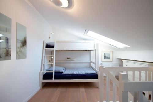 Litera blanca en habitación con escalera en STA200 Ferienwohnung Dünengras, en Timmendorfer Strand