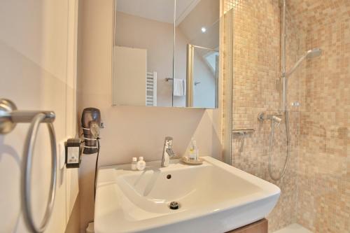 y baño blanco con lavabo y ducha. en Seeburg Appartement 26, en Scharbeutz