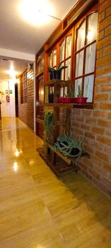 una camera con un muro di mattoni e una mensola con piante di Hospedaje Fortaleza a Oxapampa