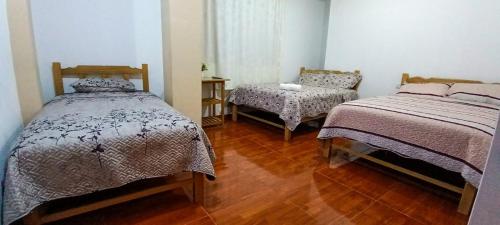 Un dormitorio con 2 camas y una silla. en Hospedaje Fortaleza, en Oxapampa