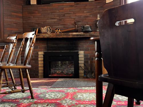a living room with chairs and a fireplace at ロッヂ秀岳 in Chikuni