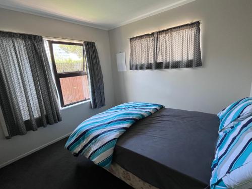 a bedroom with a bed and two windows at Stay with Benny in Nelson