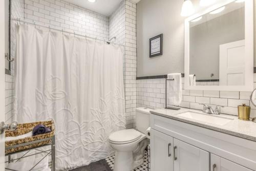 a white bathroom with a toilet and a sink at BOHO Bungalow in Tulsa