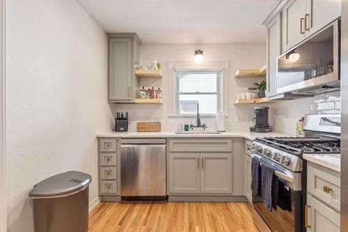 a kitchen with white cabinets and a stove top oven at Trendy in Tulsa - King Bed Expo, TU, Downtown in Tulsa