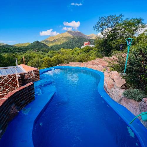 a swimming pool with blue water and mountains in the background at June en el Uritorco in Capilla del Monte