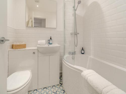 a white bathroom with a tub and a toilet and a sink at The Nest in Bempton