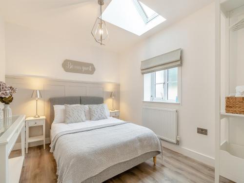 a white bedroom with a bed and a window at The Nest in Bempton