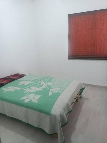 Una cama con una manta verde y blanca. en Excelente hogar para descansar, en Gómez