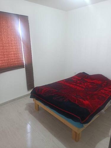 een bed in een kamer met een rode deken erop bij Excelente hogar para descansar in Gómez