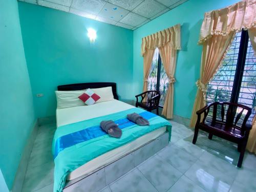 a bedroom with a bed with blue walls and windows at Thungtako Resort in Ban Samnak Pling