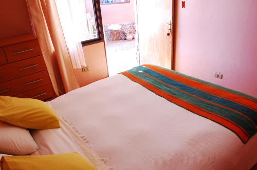 a bedroom with a large white bed with a window at Hostal Casa Turipite in San Pedro de Atacama