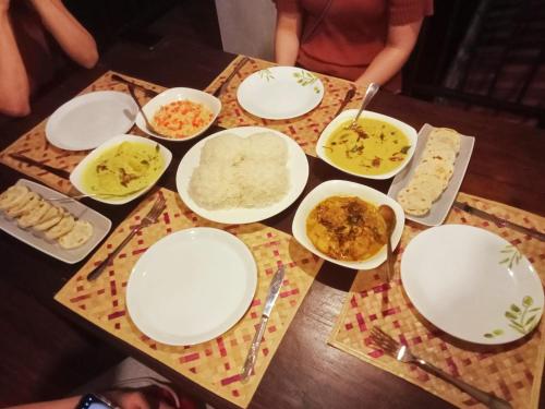a table topped with white plates and bowls of food at Ayubowan Homestay Katunayake in Katunayake