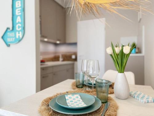 une table avec des assiettes et des verres et un vase avec des fleurs dans l'établissement Germania-22, à Sankt Peter-Ording